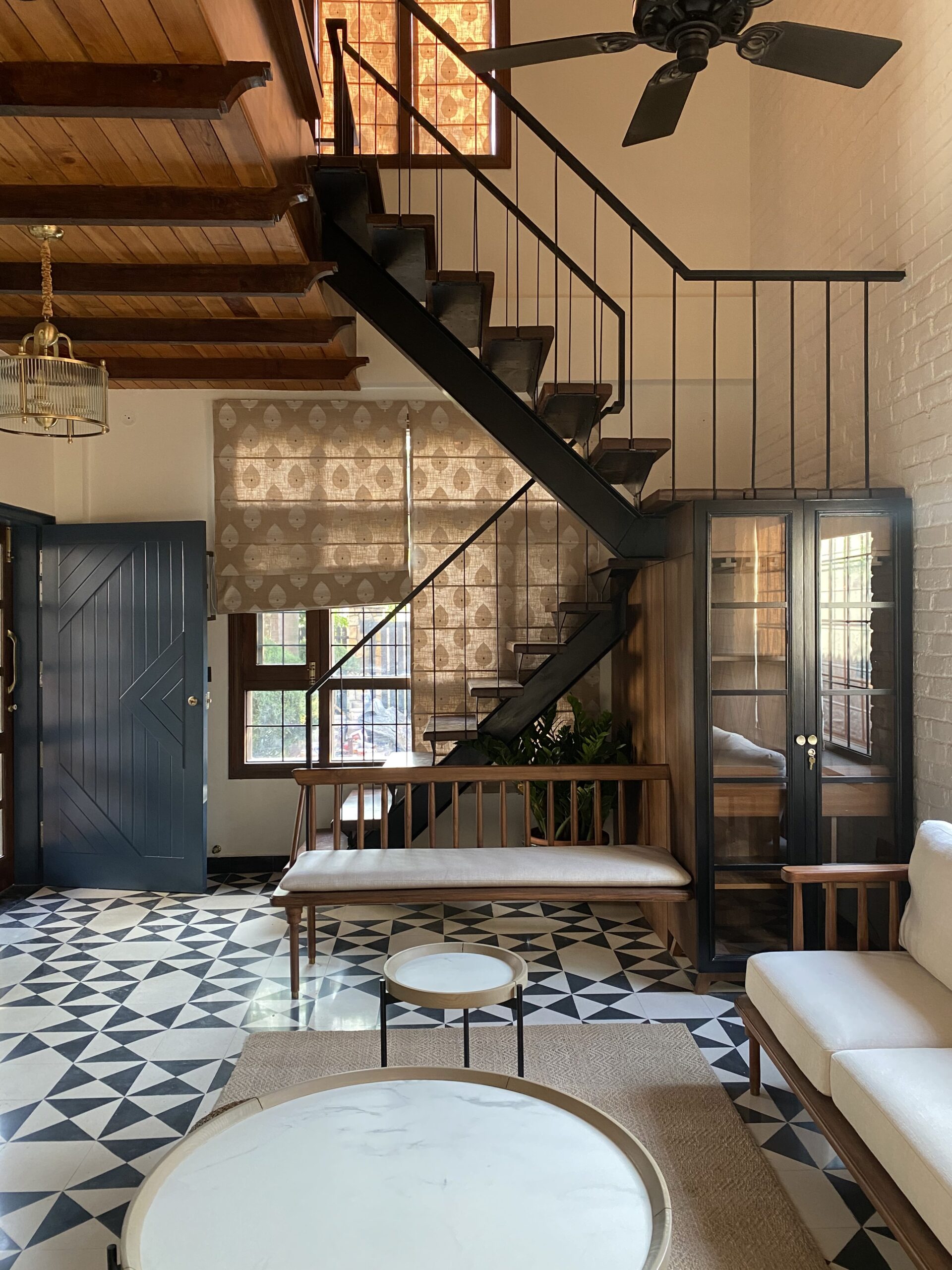 Geometric drama: Bold black-and-white triangular floor tiles create a striking foundation for this living space, echoing the clean lines of the black metal staircase.