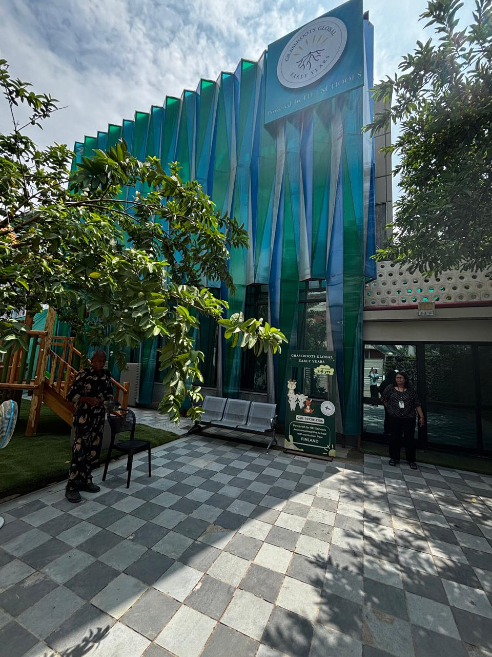 Sculpted Greenery: The striking facade features vertical, folded panels in verdant green tones, creating a rhythmic texture that mimics blades of grass and creates dynamic shadow play.