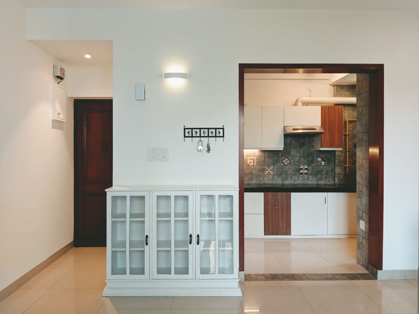 Modern Contrast: The crisp white cabinetry and walls contrast elegantly with the dark wooden door frames and the subtle geometric patterns of the kitchen backsplash tiles.