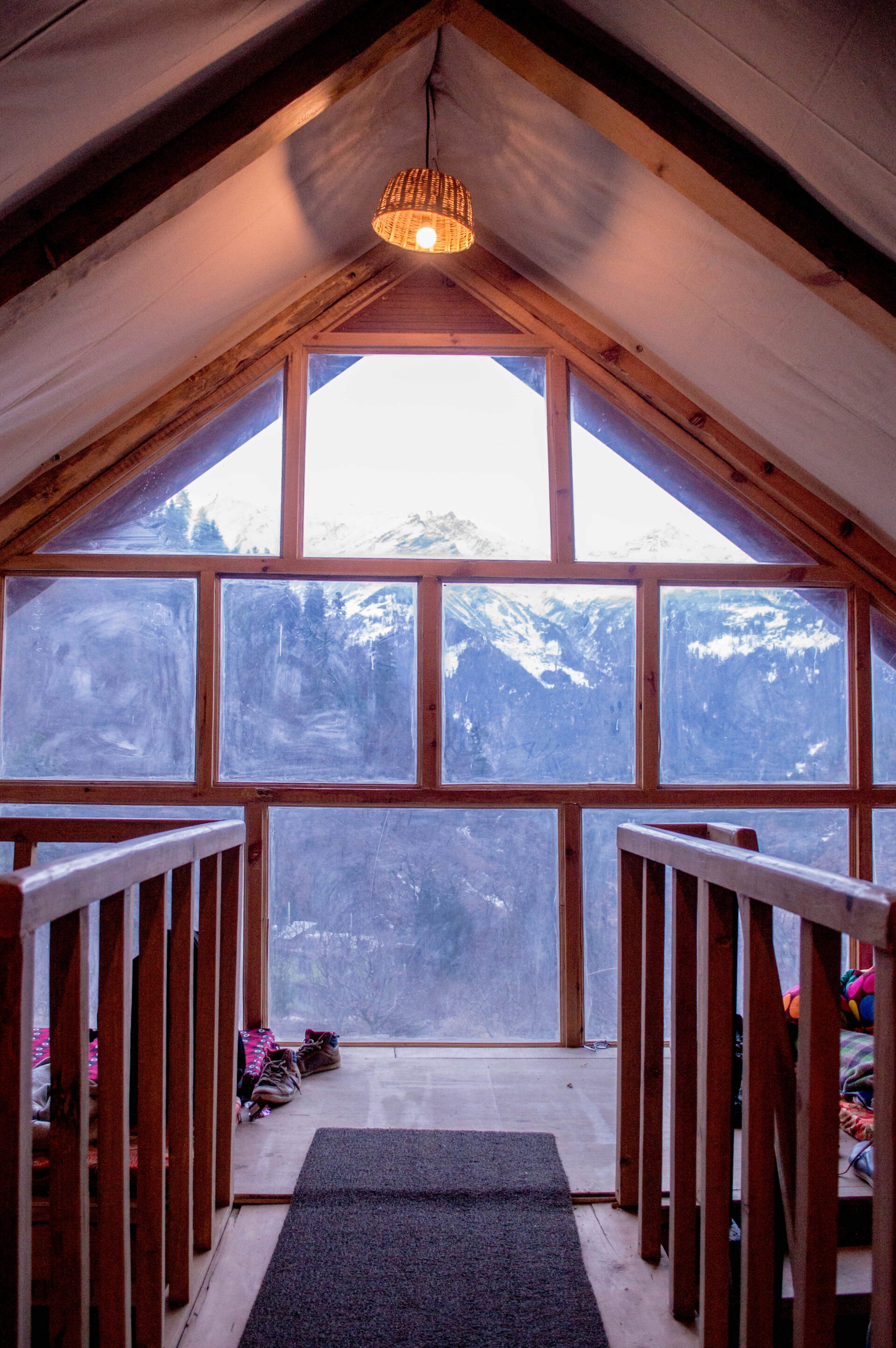 A room with a view: The triangular gable window perfectly frames the majestic snow-capped mountains, turning the landscape into a living painting for the cozy loft.