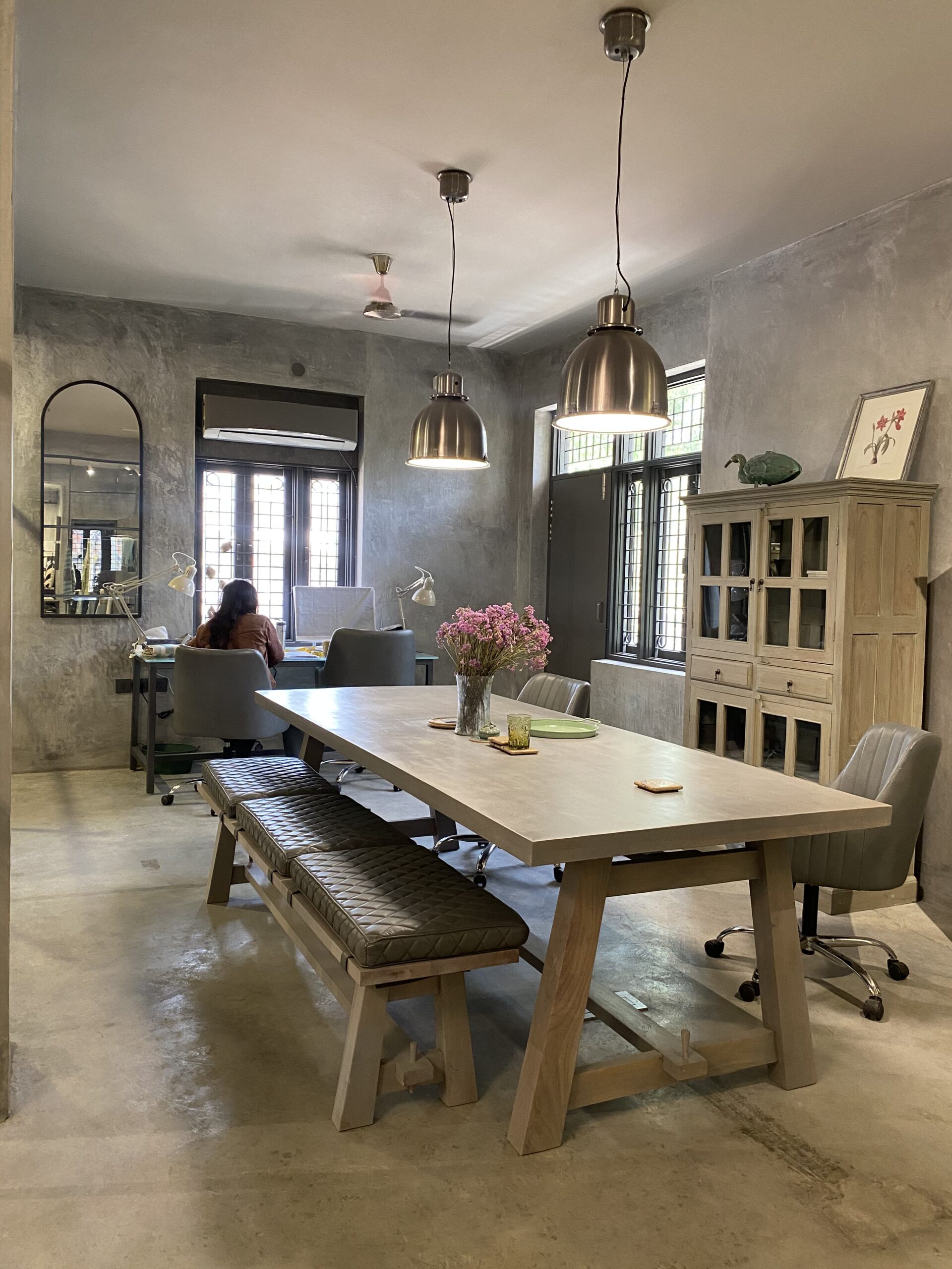 Creative collaboration: A spacious communal table anchored by industrial pendant lights serves as the heart of this raw, grey-toned office studio.