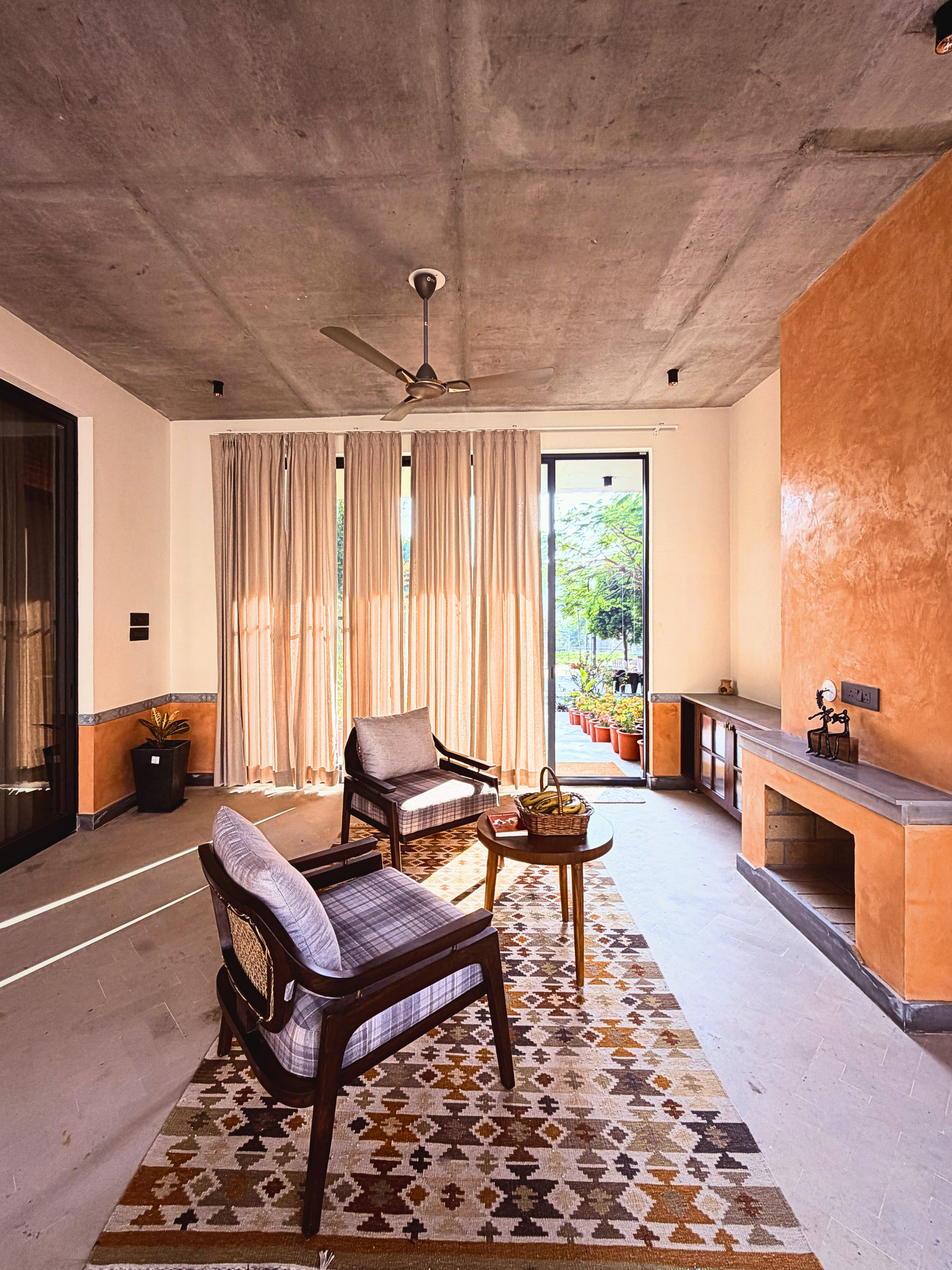 Sunlit living: Floor-to-ceiling glass doors blur the boundary between indoors and out, flooding the cozy seating area with natural light and garden views.
