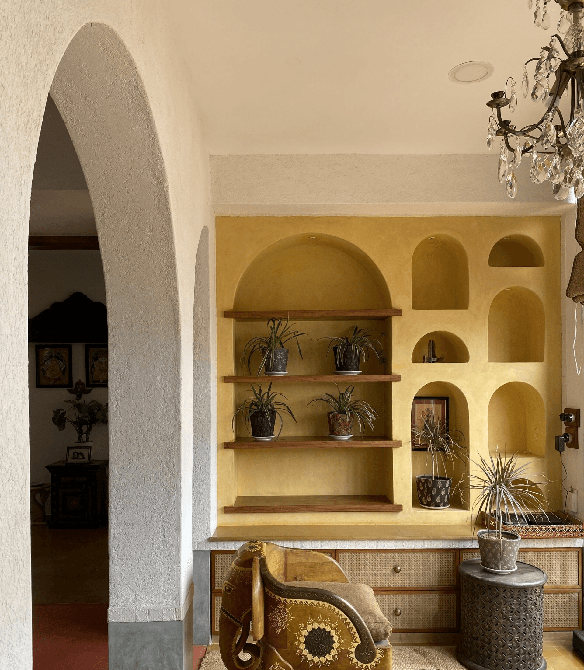 Vibrant focal point: A mustard-yellow wall niche with arched shelving introduces a pop of color and provides a dedicated display for greenery.