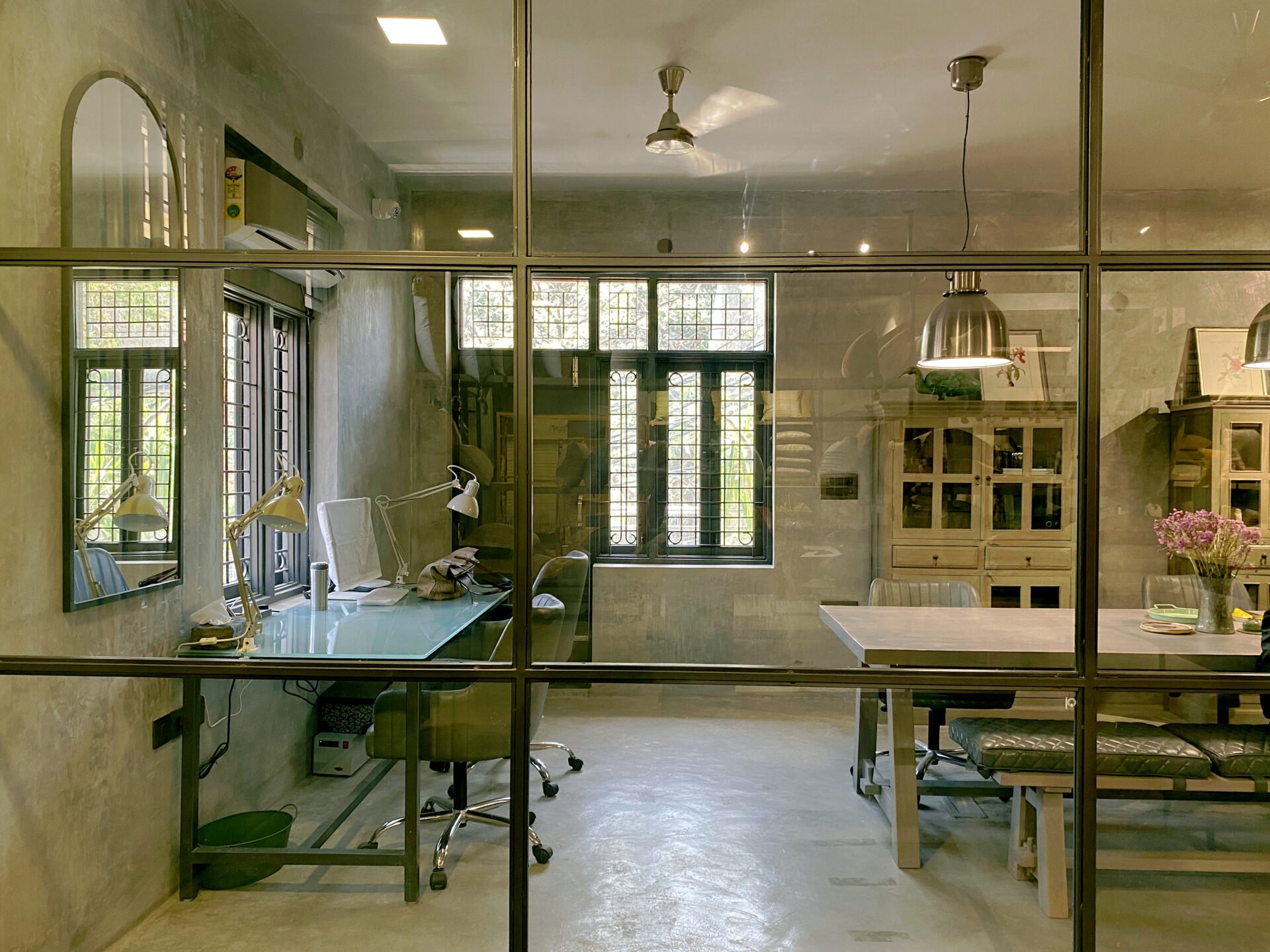 Transparency at work: A floor-to-ceiling glass partition with black metal framing separates the office area while maintaining visual continuity with the rest of the space.